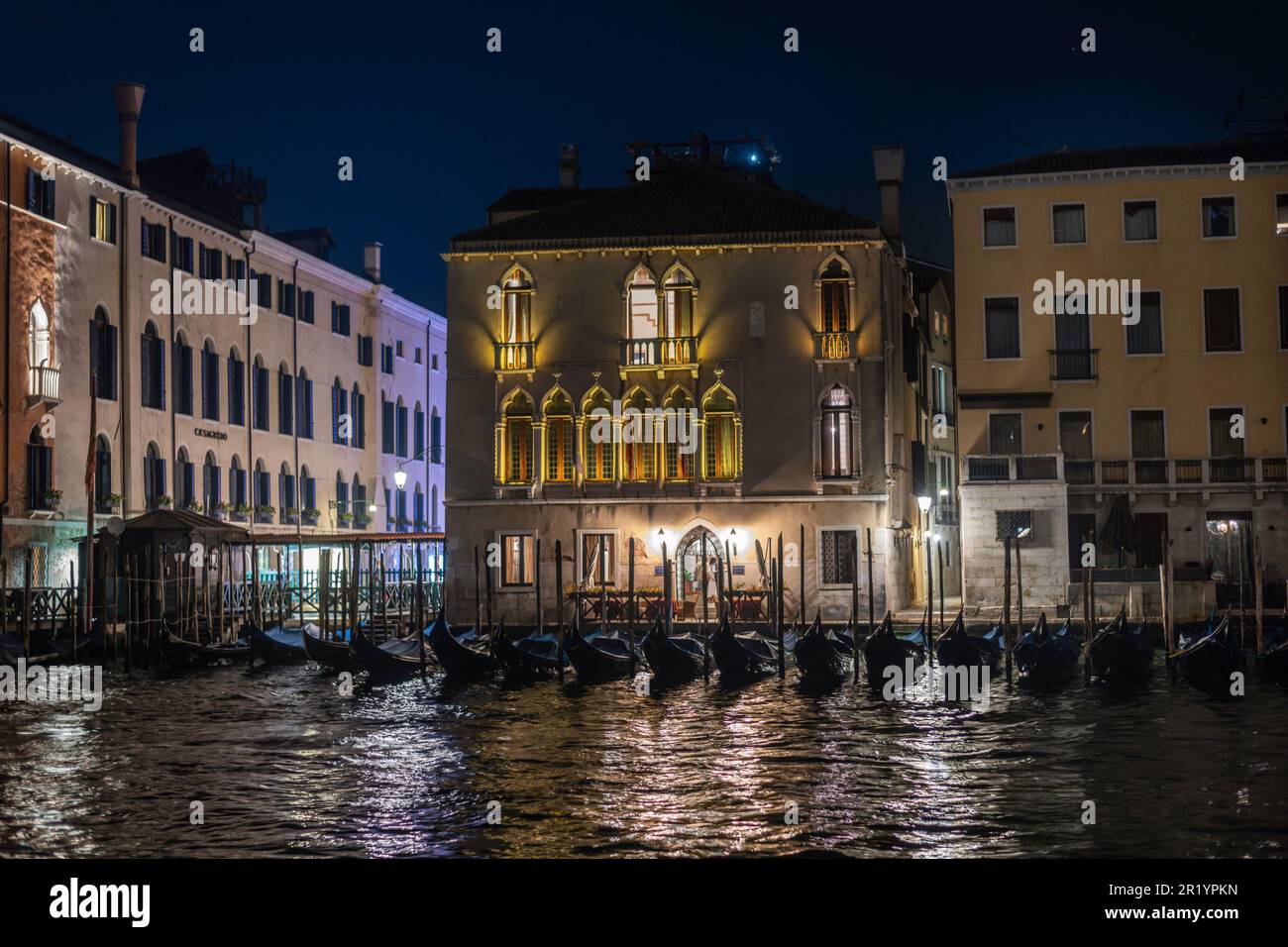 Gondole ormeggiate di notte da un palazzo veneziano sul Canal Grande Foto Stock