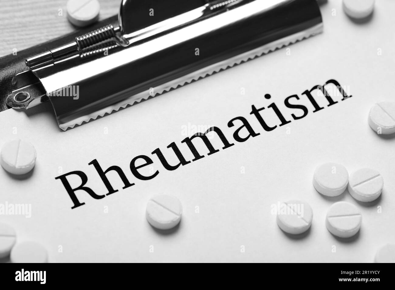 Parola Rheumatism stampato su carta bianca e pillole, primo piano Foto Stock