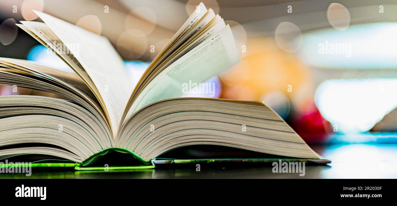 Un libro con copertina rigida aperto su un tavolo in una biblioteca pubblica Foto Stock