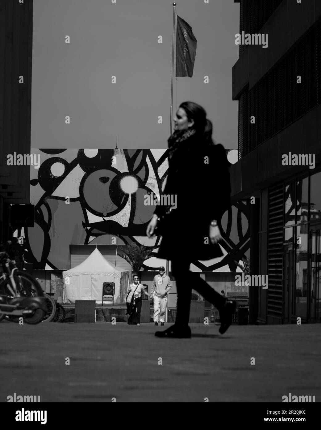 Un giovane adulto cammina lungo una strada urbana in scala di grigi Foto Stock