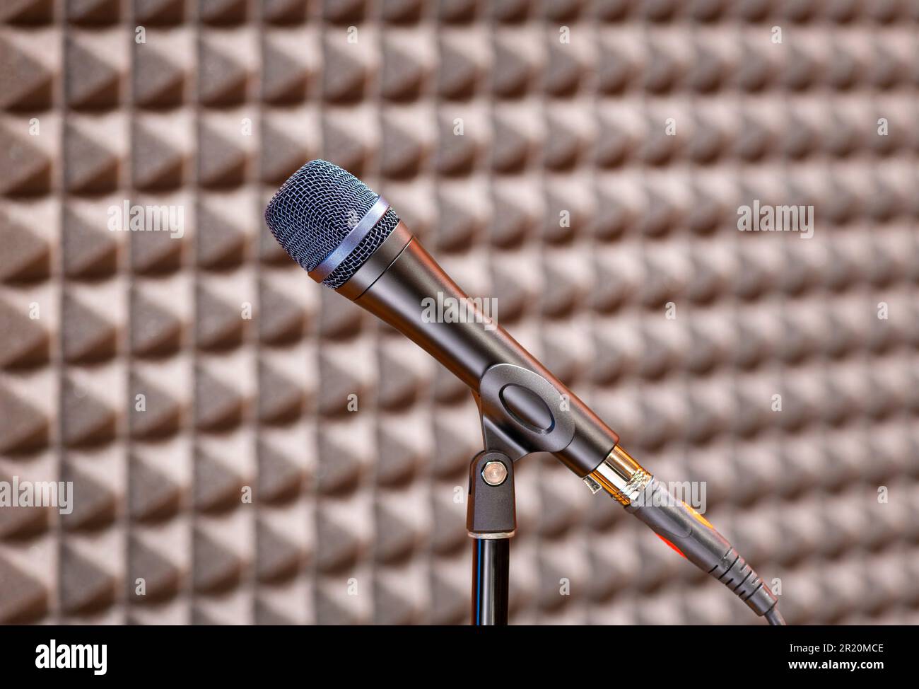 Moderno microfono elettrico professionale collocato in uno studio di registrazione vicino alla parete su sfondo sfocato Foto Stock