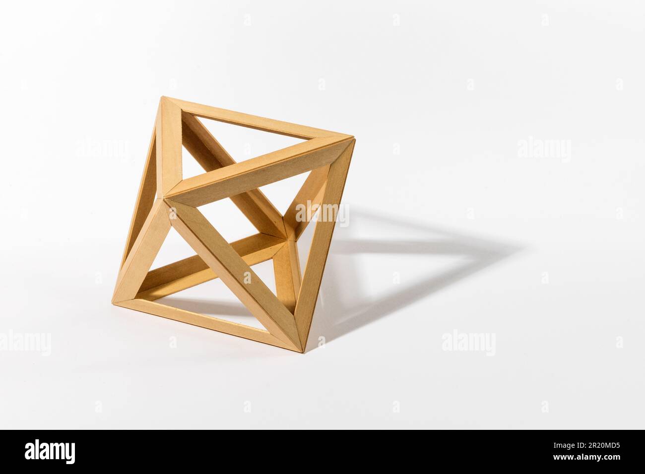 Forma ottaedrica solida platonica costituita da parti in legno che gettano l'ombra su sfondo grigio Foto Stock