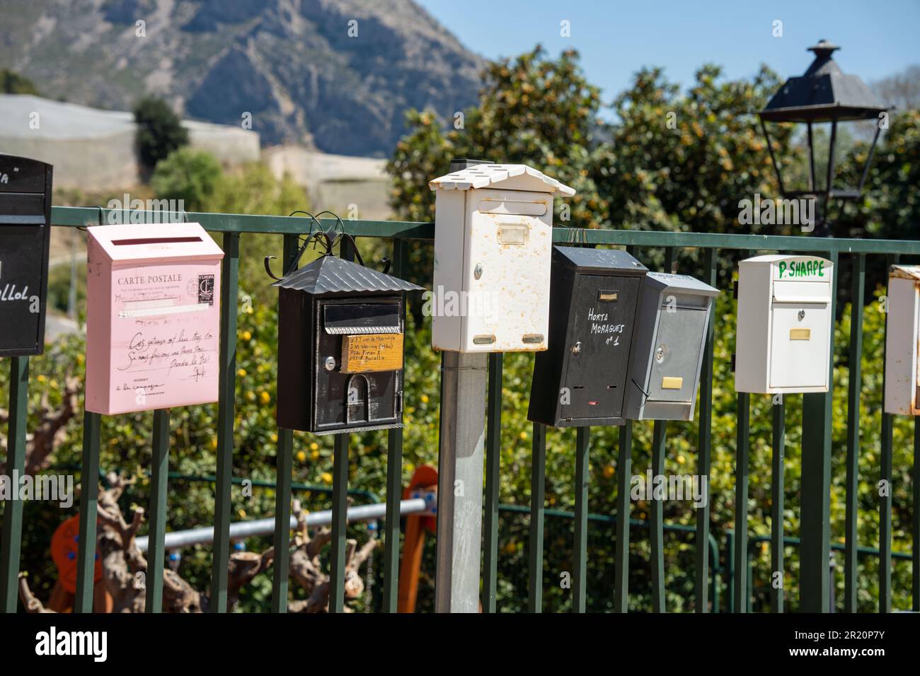 varie cassette postali colorate lungo il lato della strada Foto Stock