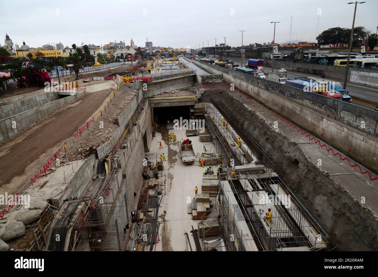 Cantiere di tunnel sotto il fiume Rimac per una nuova autostrada e linea gialla Via Expresa linea autobus, Lima, Perù. Il tunnel si estende per 1,8km km sotto il fiume Rimac, che è stato deviato per consentire la costruzione. I lavori sono iniziati nel gennaio 2012 e hanno richiesto 6 anni, il tunnel è stato aperto nel giugno 2018. La società brasiliana OAS costruì il tunnel. Le 2 torri sullo sfondo più a sinistra sono la cattedrale nel centro storico. Foto Stock