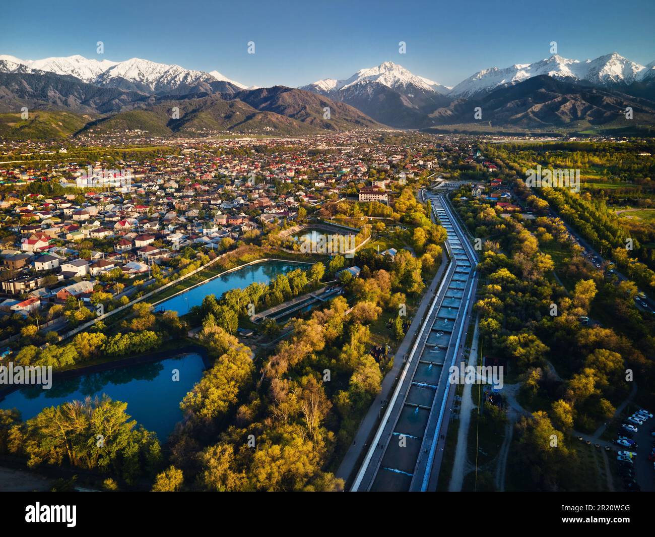 Vista aerea del drone panorama del grande fiume Almaty e le case con scenario di montagne di neve sullo sfondo nella città di Almaty, Kazakistan Foto Stock