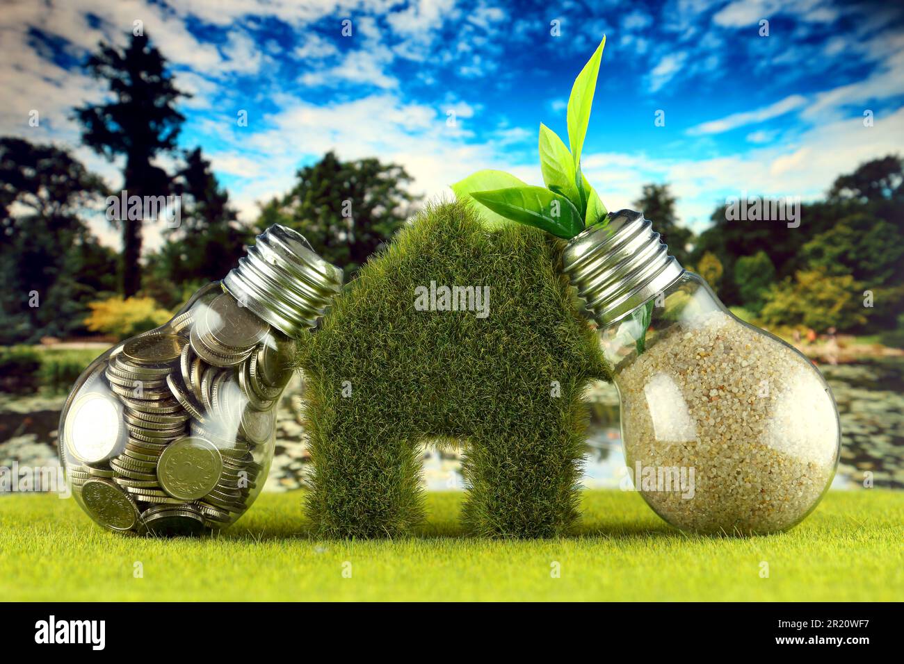 Monete all'interno della lampadina, pianta che cresce all'interno della lampadina e casa in miniatura con erba. Eco-verde energia rinnovabile concetto. Prezzo dell'elettricità Foto Stock