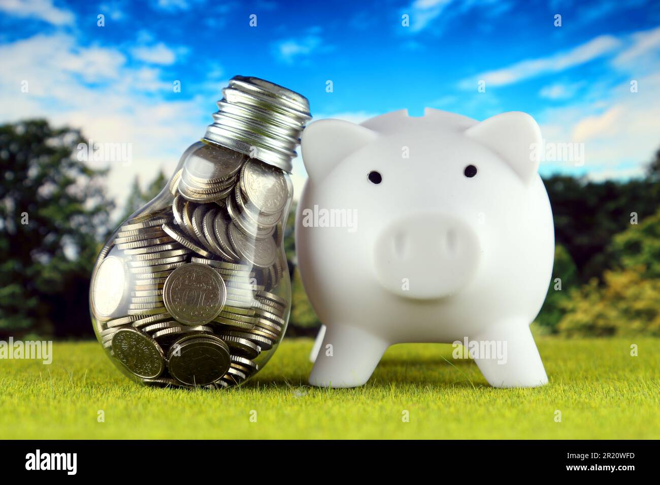 Monete all'interno della lampadina e del banco di porcellini. Eco-verde energia rinnovabile concetto. I prezzi dell'elettricità, il risparmio energetico in famiglia. Foto Stock