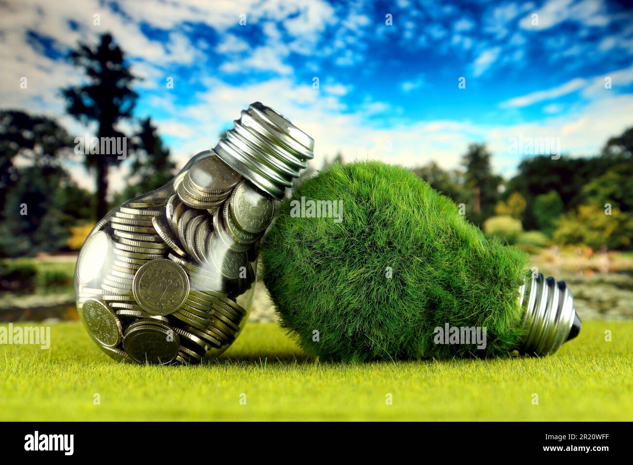 Monete all'interno della lampadina e lampadina verde eco con erba. Concetto di energia rinnovabile. I prezzi dell'elettricità, il risparmio energetico in famiglia. Foto Stock