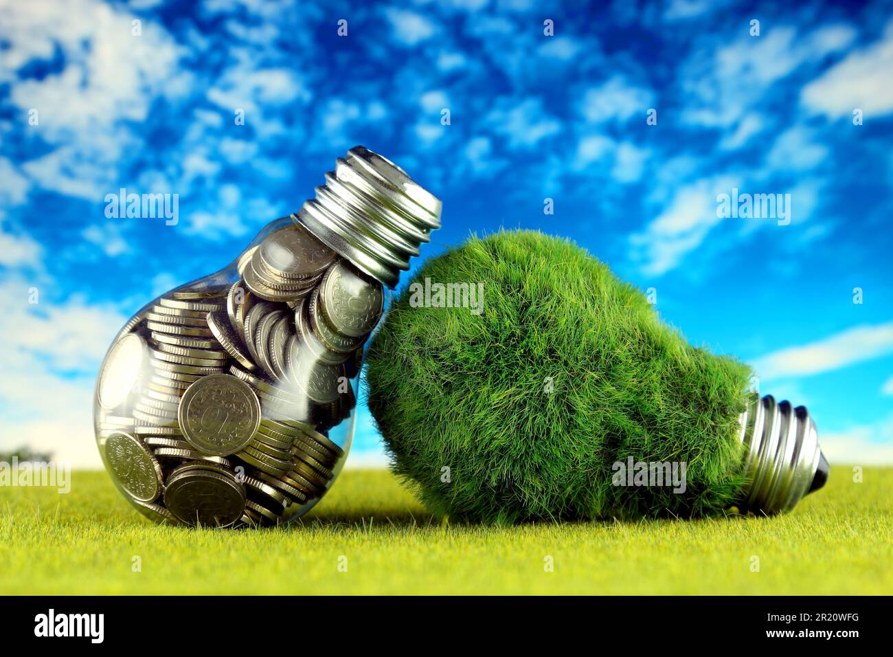 Monete all'interno della lampadina e lampadina verde eco con erba. Concetto di energia rinnovabile. I prezzi dell'elettricità, il risparmio energetico in famiglia. Foto Stock