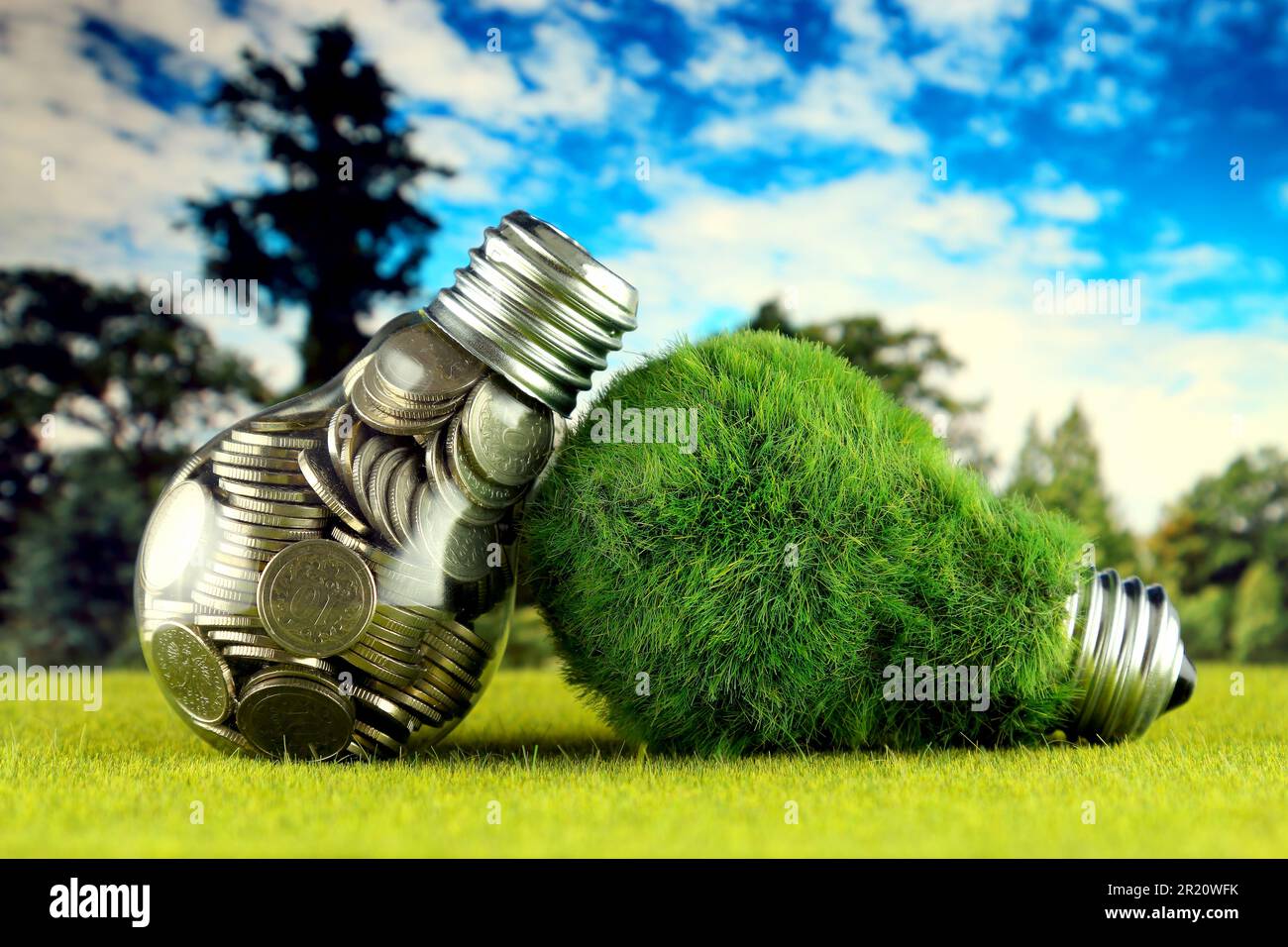 Monete all'interno della lampadina e lampadina verde eco con erba. Concetto di energia rinnovabile. I prezzi dell'elettricità, il risparmio energetico in famiglia. Foto Stock