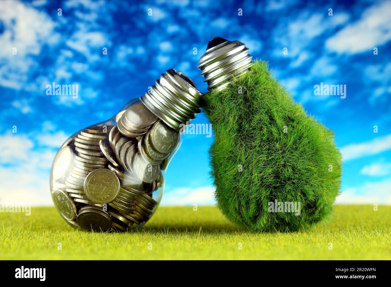 Monete all'interno della lampadina e lampadina verde eco con erba. Concetto di energia rinnovabile. I prezzi dell'elettricità, il risparmio energetico in famiglia. Foto Stock