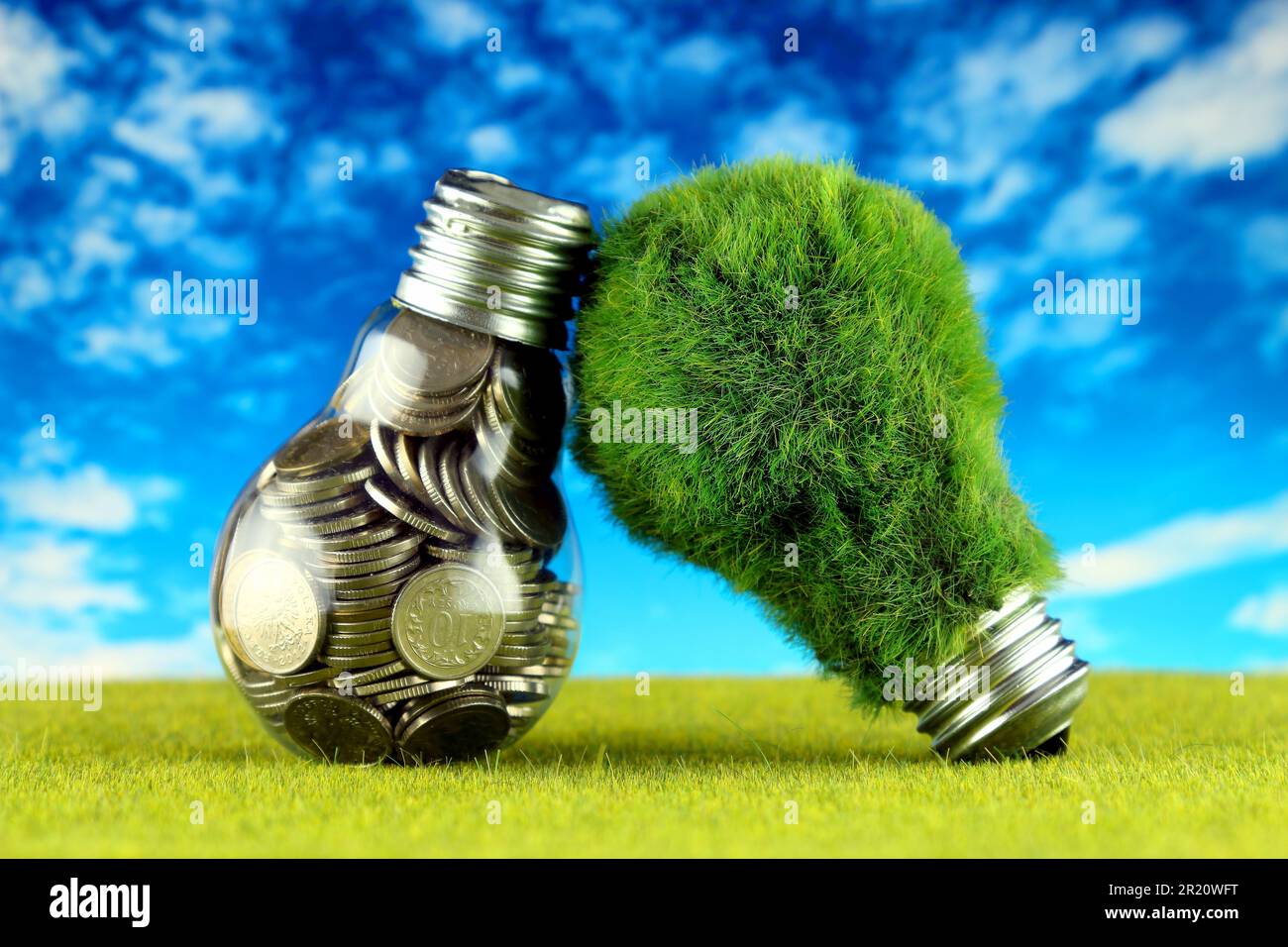 Monete all'interno della lampadina e lampadina verde eco con erba. Concetto di energia rinnovabile. I prezzi dell'elettricità, il risparmio energetico in famiglia. Foto Stock