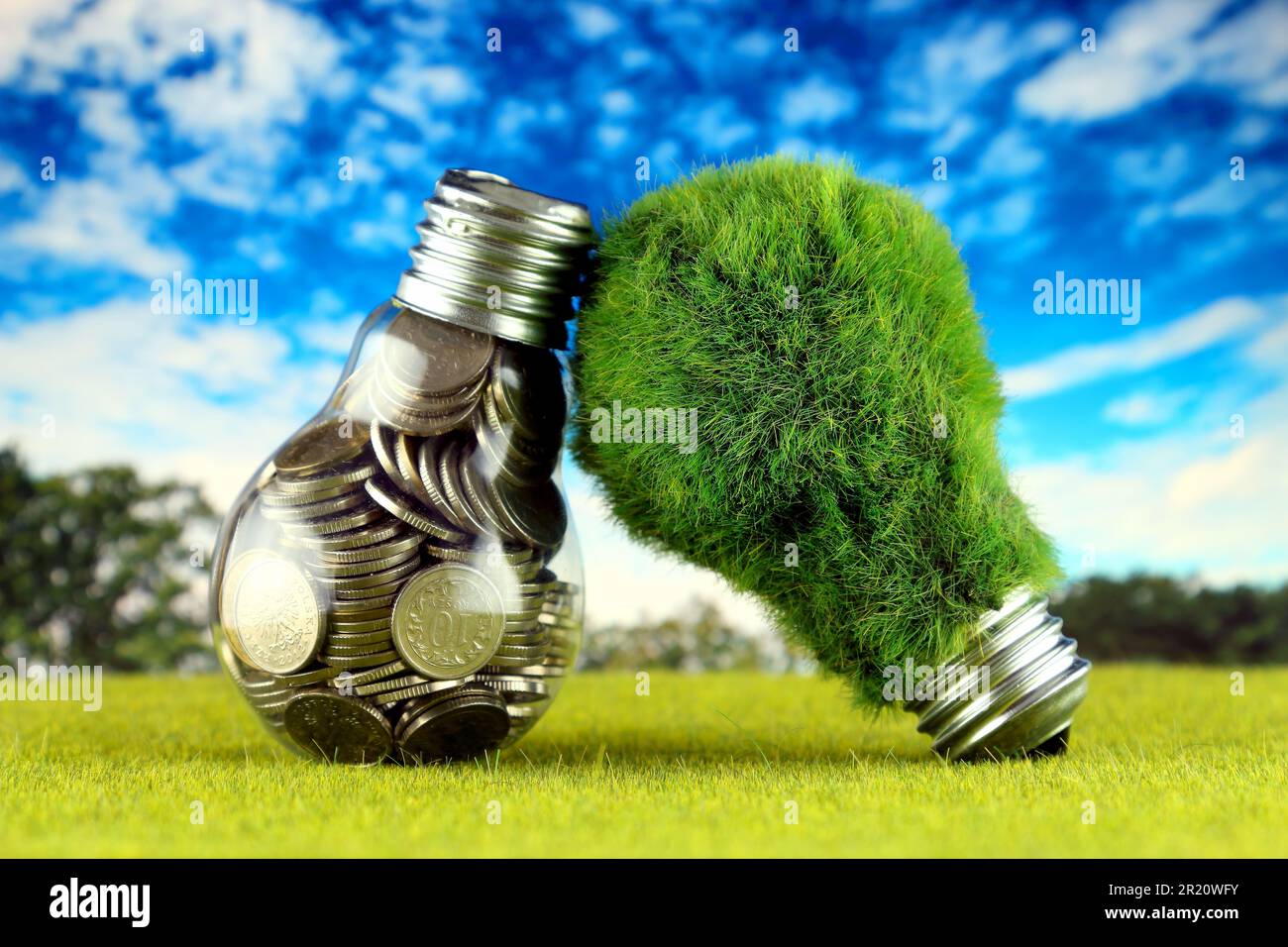 Monete all'interno della lampadina e lampadina verde eco con erba. Concetto di energia rinnovabile. I prezzi dell'elettricità, il risparmio energetico in famiglia. Foto Stock