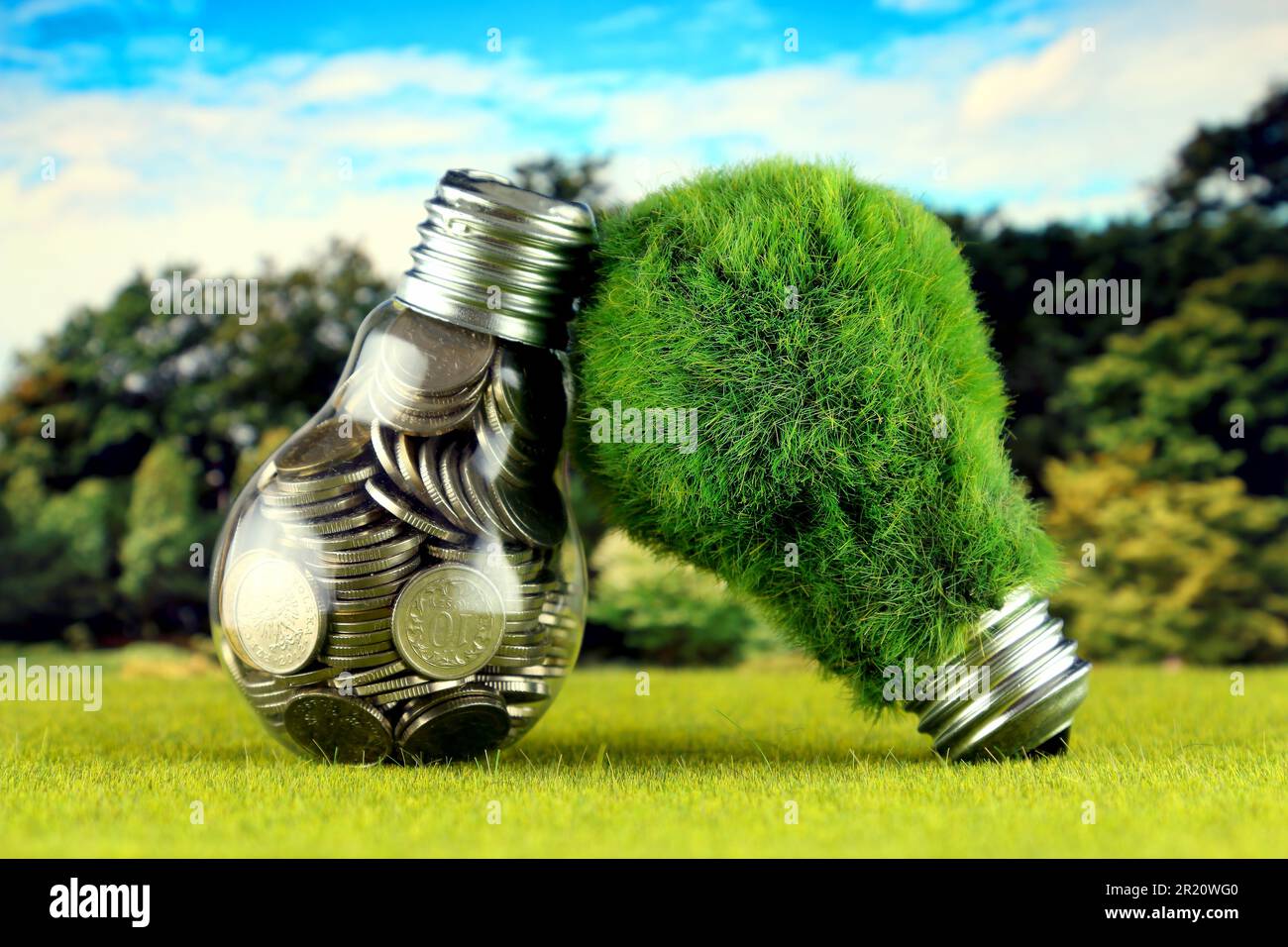 Monete all'interno della lampadina e lampadina verde eco con erba. Concetto di energia rinnovabile. I prezzi dell'elettricità, il risparmio energetico in famiglia. Foto Stock