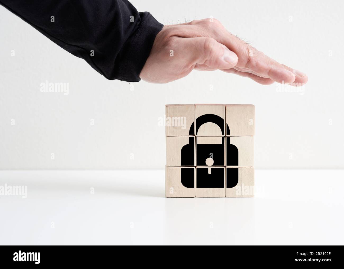Concetto di sicurezza e protezione. Privacy o sicurezza dei dati o dell'identità. Mano protettiva sui cubetti di legno con icona a forma di lucchetto. Foto Stock