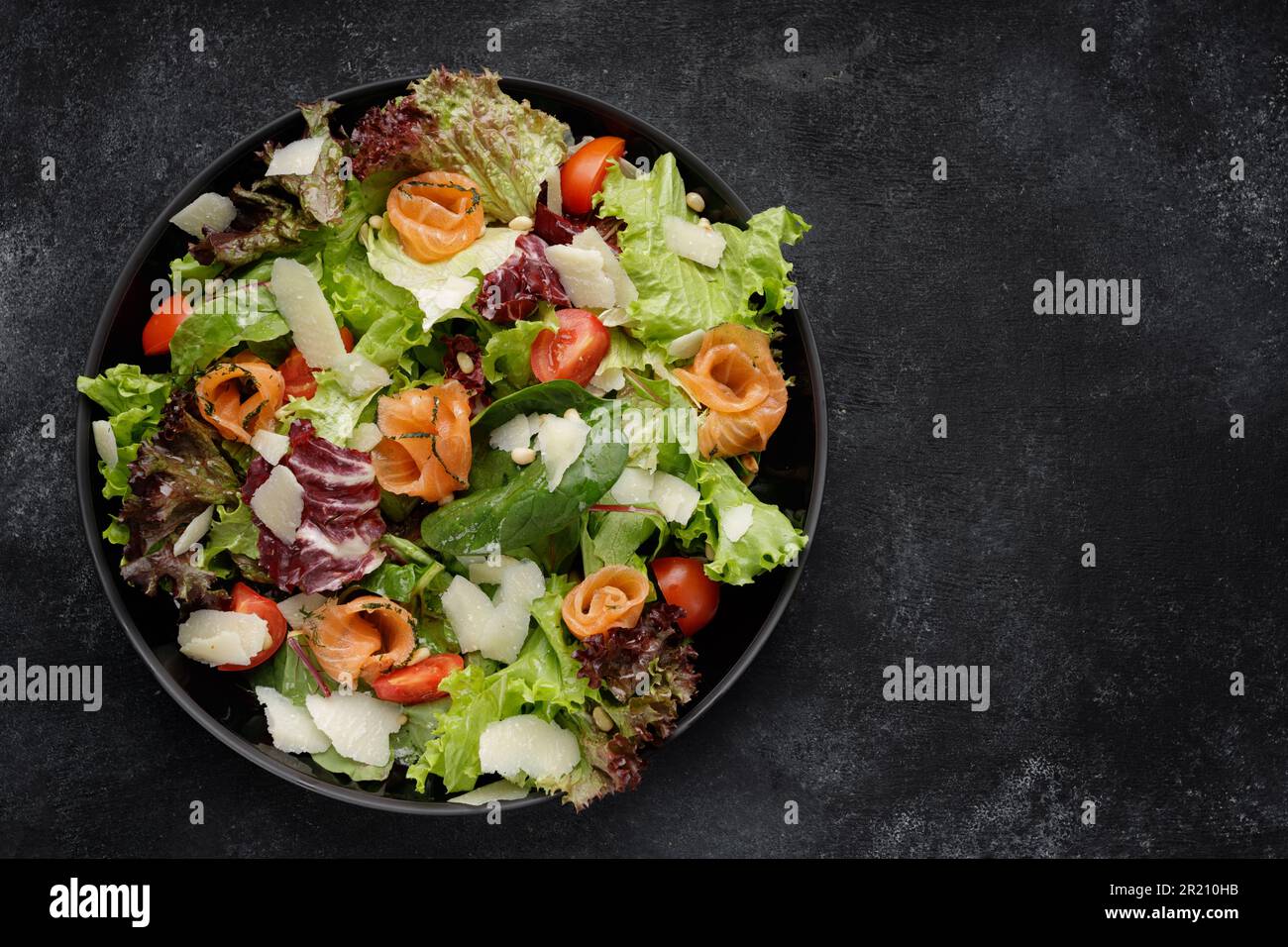 Insalata deliziosa con salmone, parmigiano, pomodori e verdure miste Foto Stock