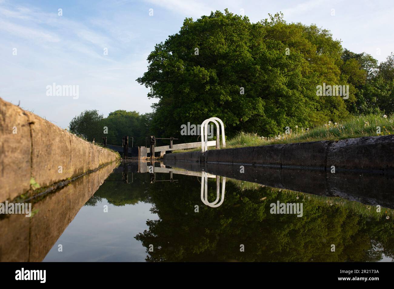 Blocca e blocca i cancelli a Tyrley Locks sul canale Shropshire Union in Inghilterra. Alberi riflessi in acqua ferma in una mattina di sole Foto Stock
