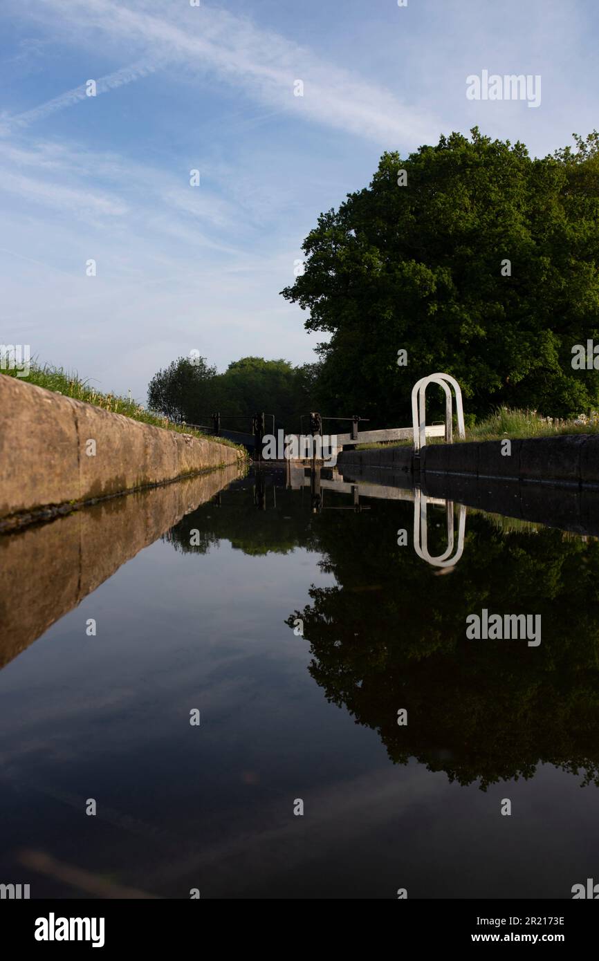 Blocca e blocca i cancelli a Tyrley Locks sul canale Shropshire Union in Inghilterra. Alberi riflessi in acqua ferma in una mattina di sole Foto Stock