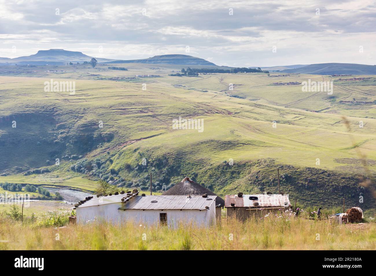 Case rurali nei monti Drakensburg a Kwa-Zulu Natal con vista sulla valle e le colline e il cielo nuvoloso Foto Stock