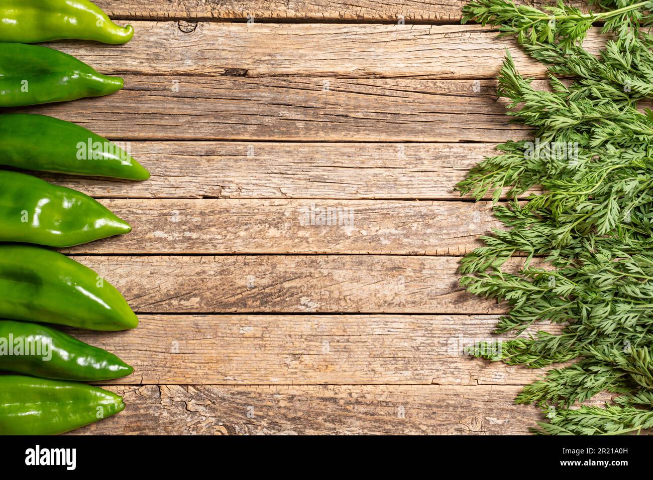 Fondo rustico in legno con peperoni ed erbe ai lati. Foto Stock