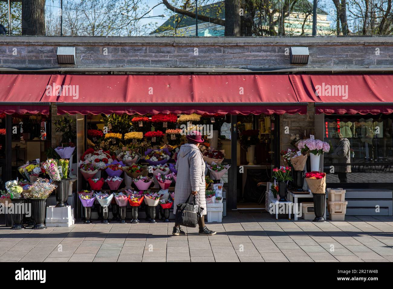 Donna che passa accanto al negozio di fiori a Viru tänav a Tallinn, Estonia Foto Stock
