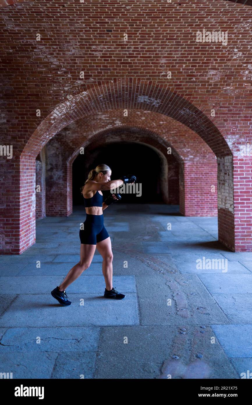 Bella giovane donna coraggiosa Shadow Boxing in un vecchio forte di mattoni Foto Stock
