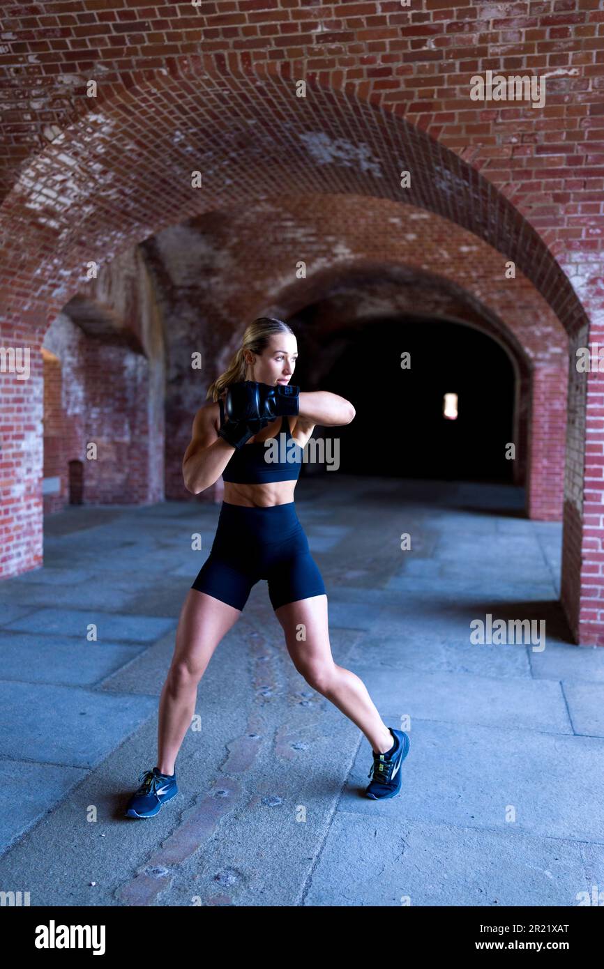 Bella giovane donna coraggiosa Shadow Boxing in un vecchio forte di mattoni Foto Stock