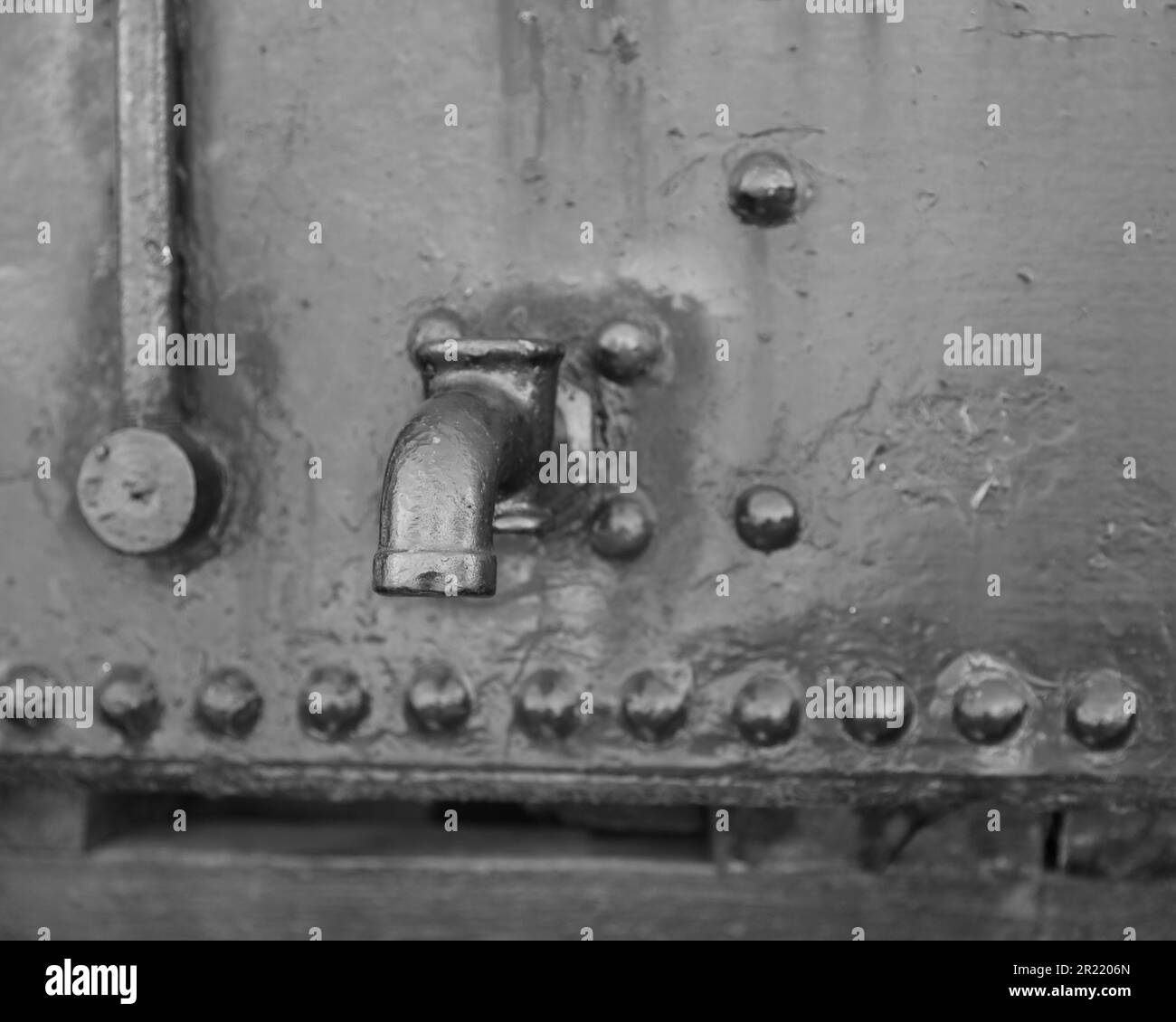Un primo piano in scala di grigi di un rubinetto d'acciaio su una superficie metallica Foto Stock