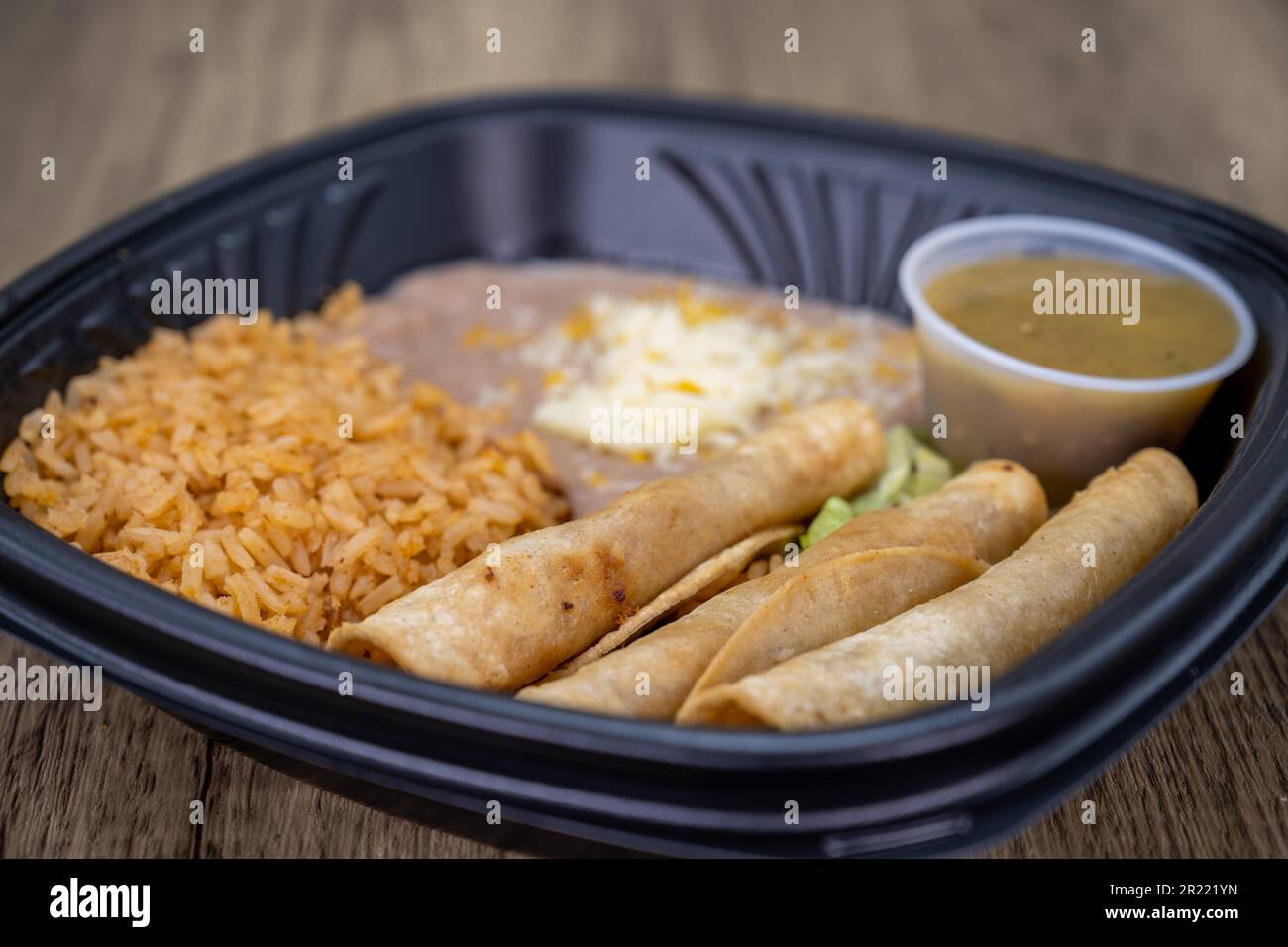 Per andare ordine di taquitos, riso, e fagioli combinazione pasto tutto imballato in contenitore di plastica e pronto per andare. Foto Stock