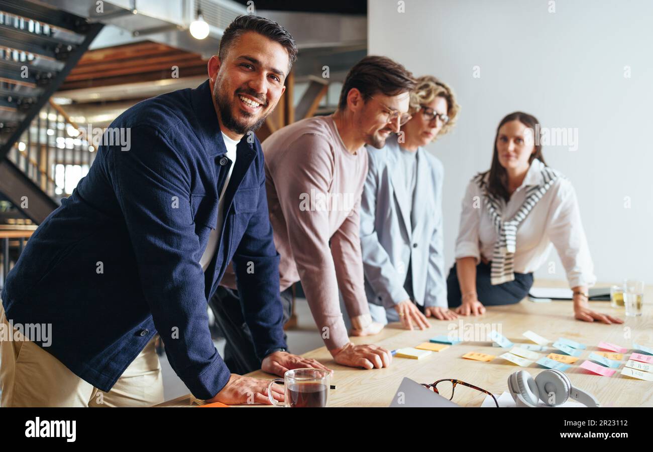 Uomo d'affari felice che ha un incontro con il suo team in un'agenzia pubblicitaria. Gente creativa di affari che discute le idee in un ufficio. Gruppo di profissio Foto Stock