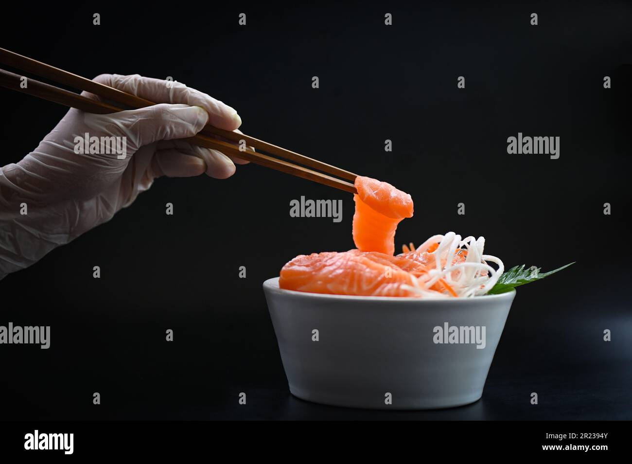 salmone sashimi cibo filetto di salmone menu giapponese con le mani tenevano le bacchette per tenere il salmone sashimi, salmone fresco crudo pesce per la cottura f Foto Stock