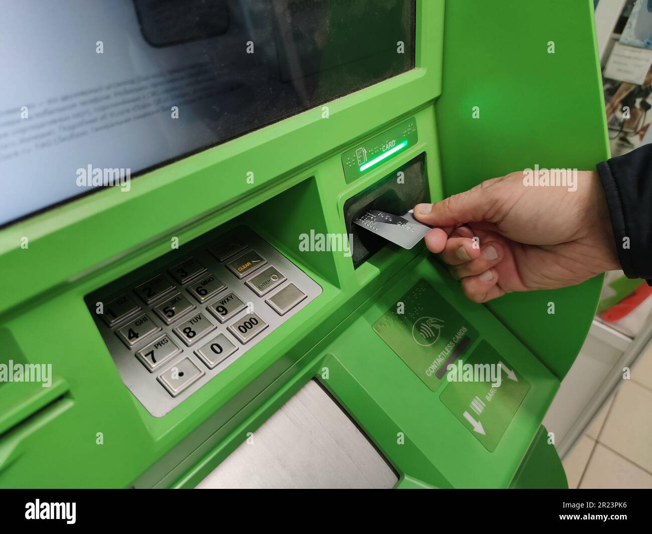 Primo piano della mano dell'uomo inserendo la e-card nello slot ATM Foto Stock