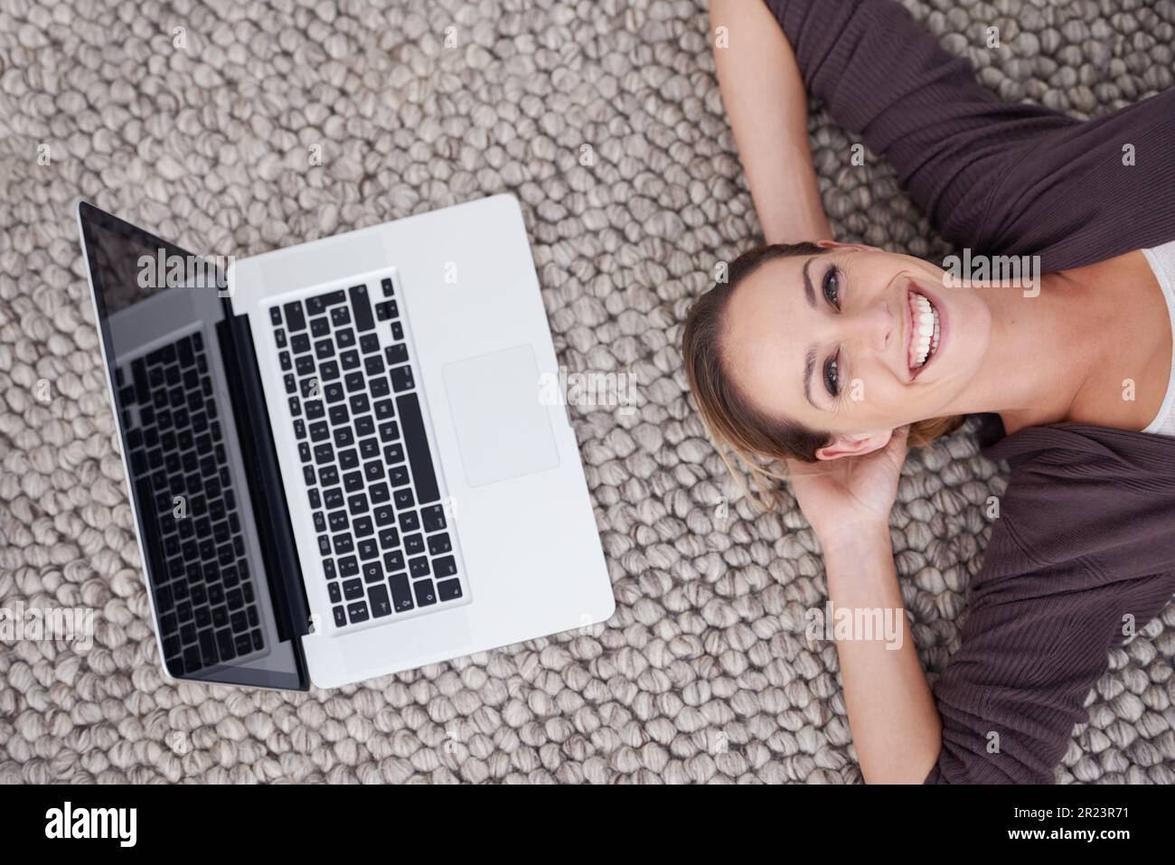 Connessi, ovunque e in qualsiasi momento. Scatto ad angolo alto di una giovane donna sdraiata sul pavimento con il suo notebook. Foto Stock