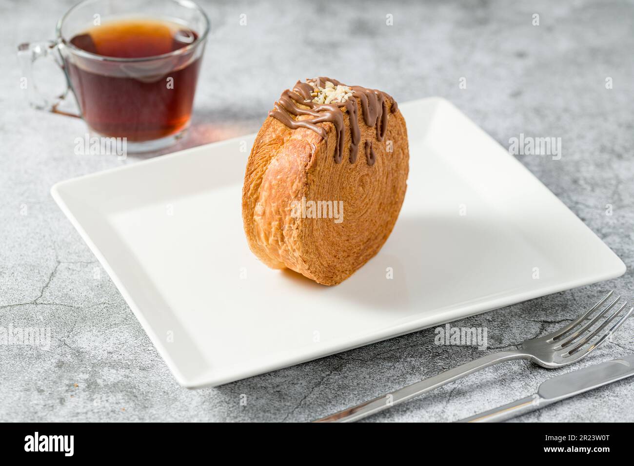 Rotolo di cioccolato New York o croissant rotondo con tè su tavolo di pietra Foto Stock