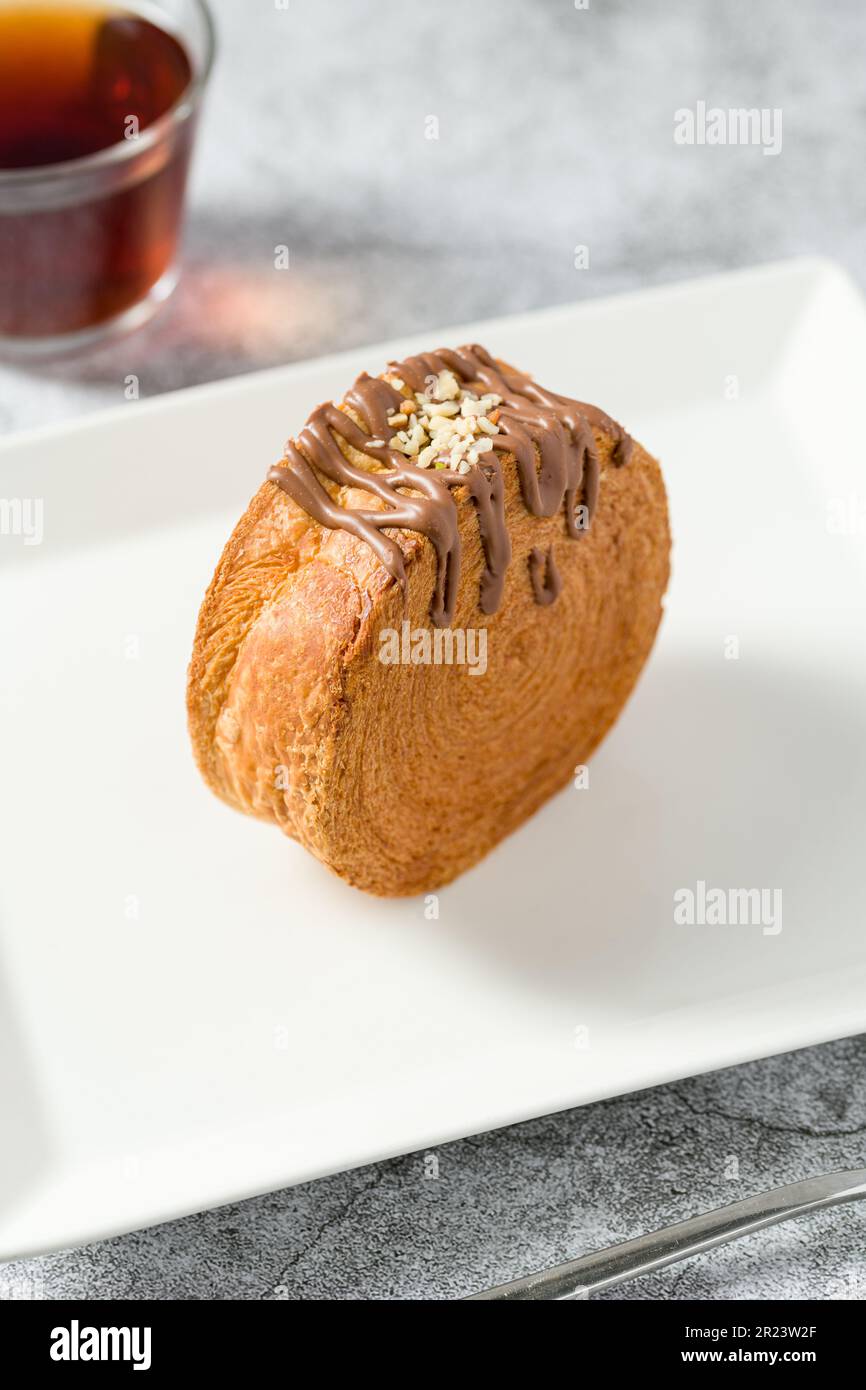 Rotolo di cioccolato New York o croissant rotondo con tè su tavolo di pietra Foto Stock