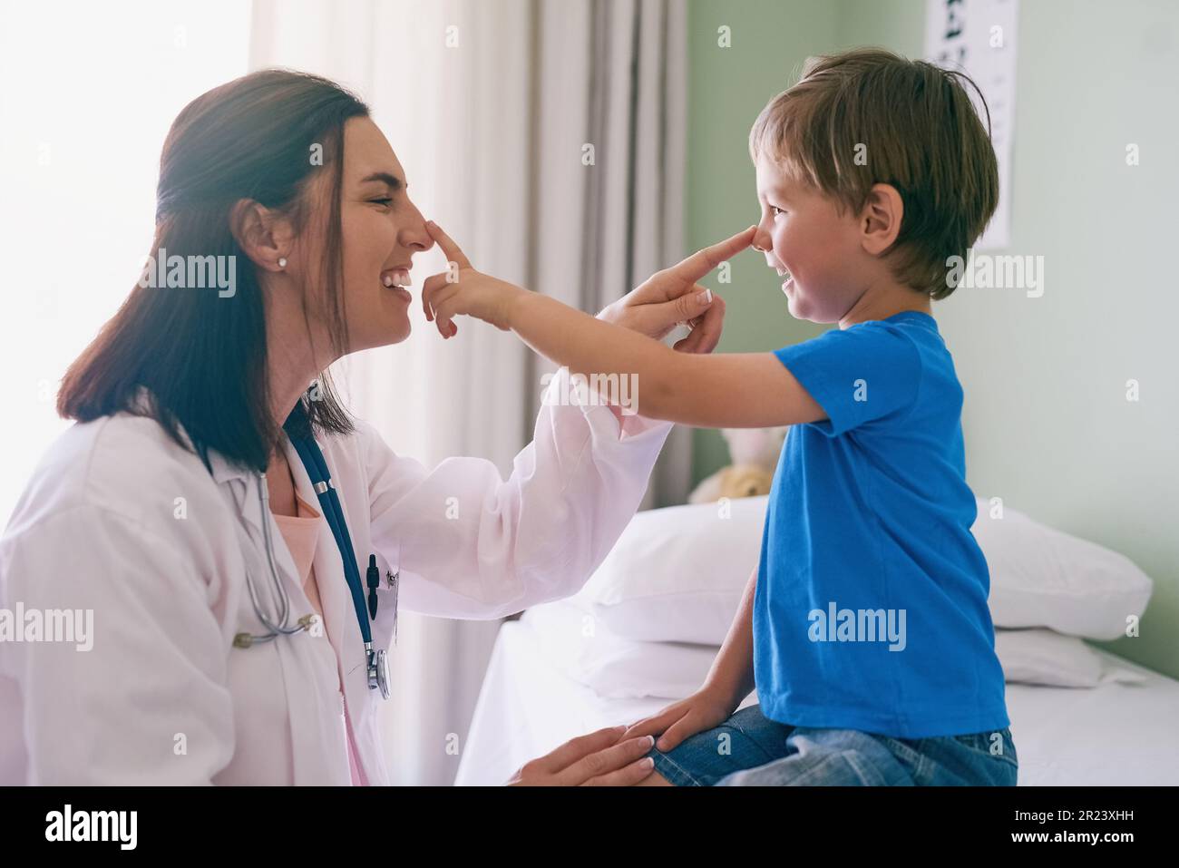 Donna medico, giocare e bambino in un ospedale per la salute e la consultazione medica. Divertimento, poke naso e pediatra lavorando con una risata e. Foto Stock