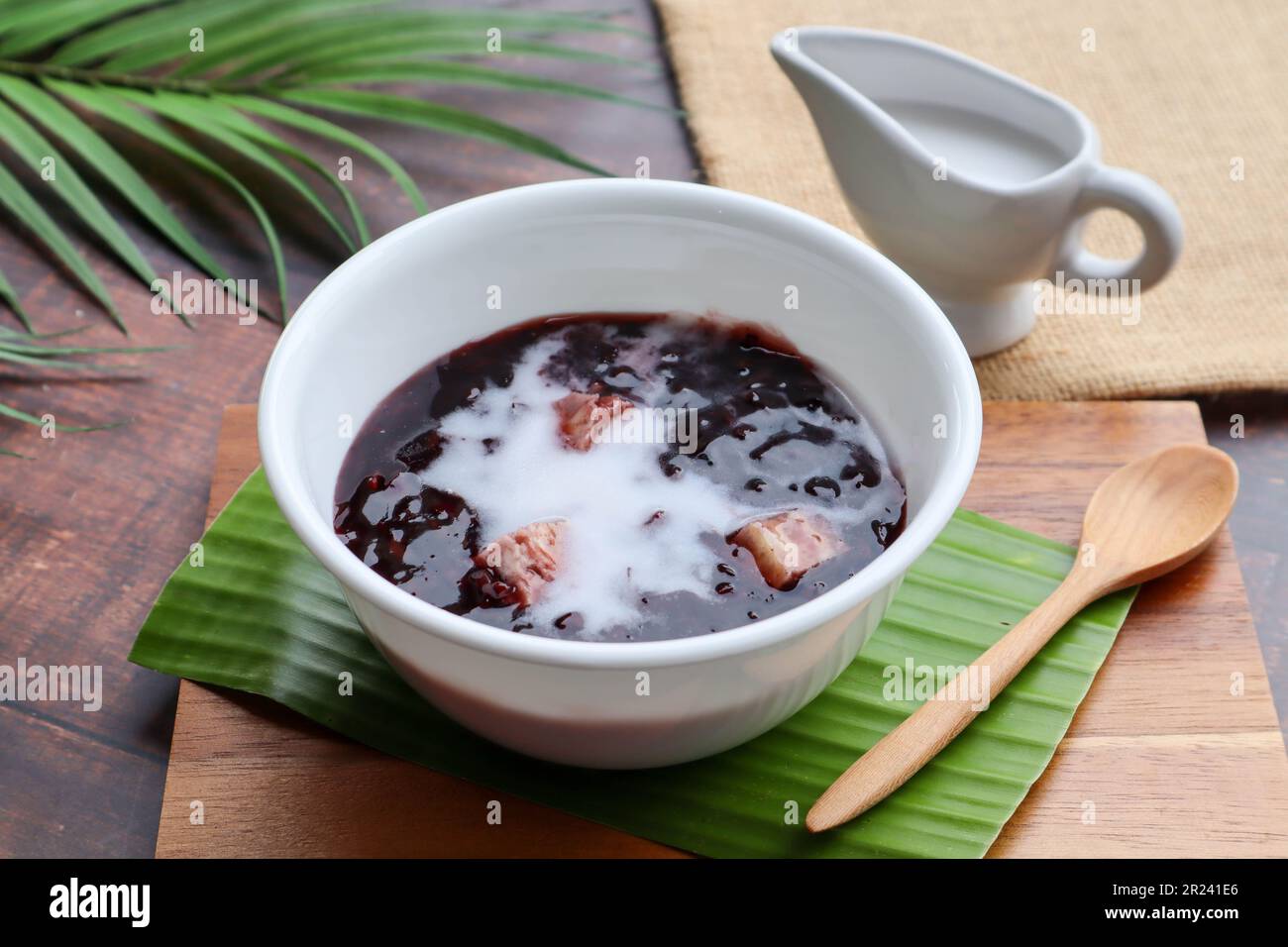 Budino di riso nero appiccicoso con taro e latte di cocco alla vista superiore della tavola di legno, riso glutinoso nero - dessert tailandese chiamato Khao Nieow Dam Foto Stock