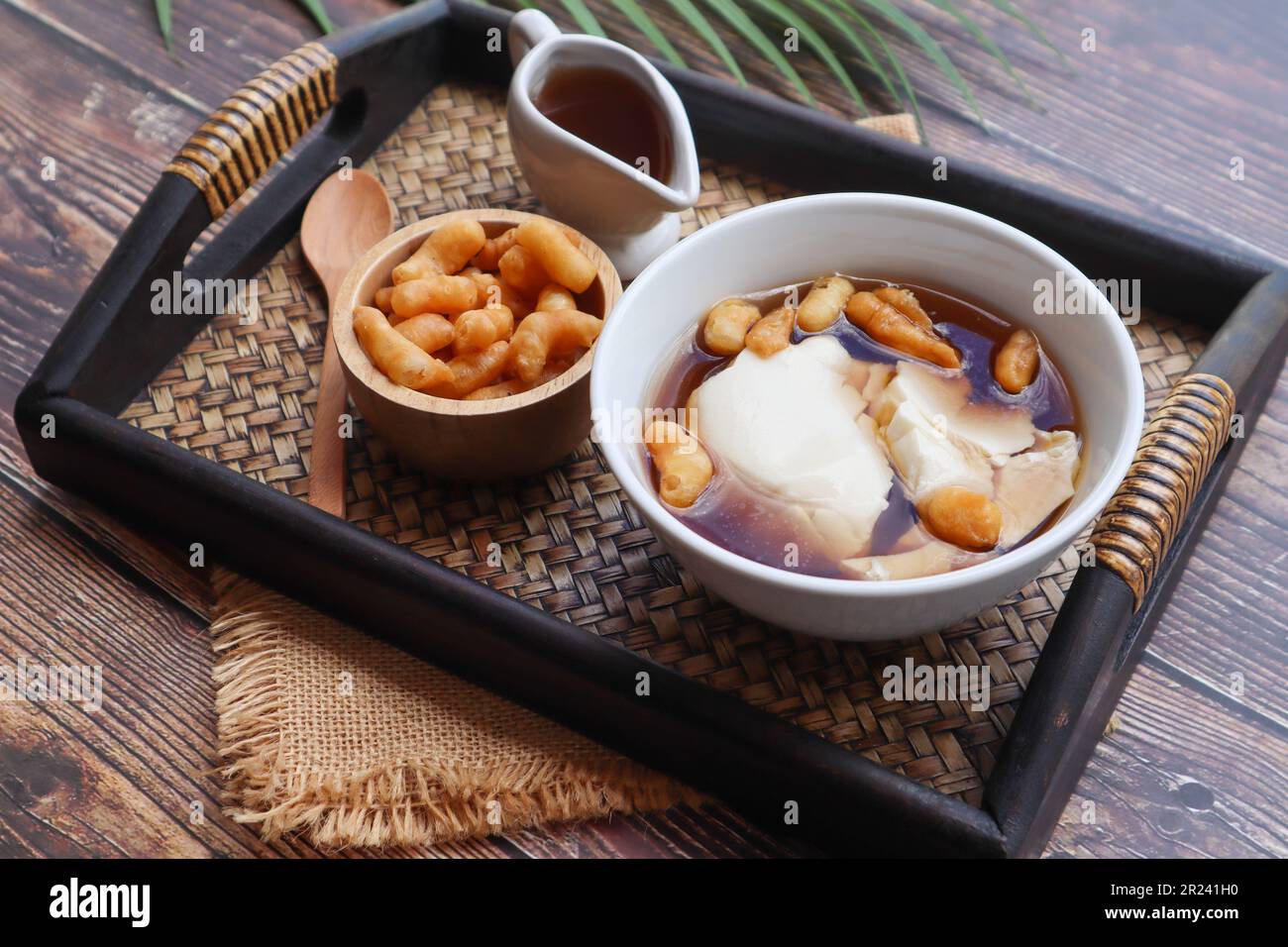 Douhua - soffice budino di tofu (cagliata di soia), famoso dessert sano asiatico servito in un vassoio di bambù di tavolo di legno a vista ravvicinata Foto Stock