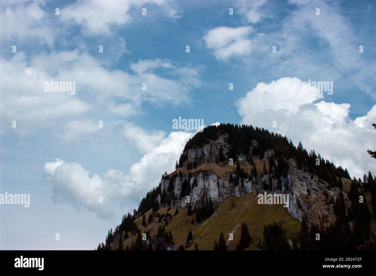 Tavolozza della natura: Un pittoresco paesaggio montano risveglia in vivaci colori primaverili, come serene nuvole blu incorniciano con grazia la scena mozzafiato. Foto Stock