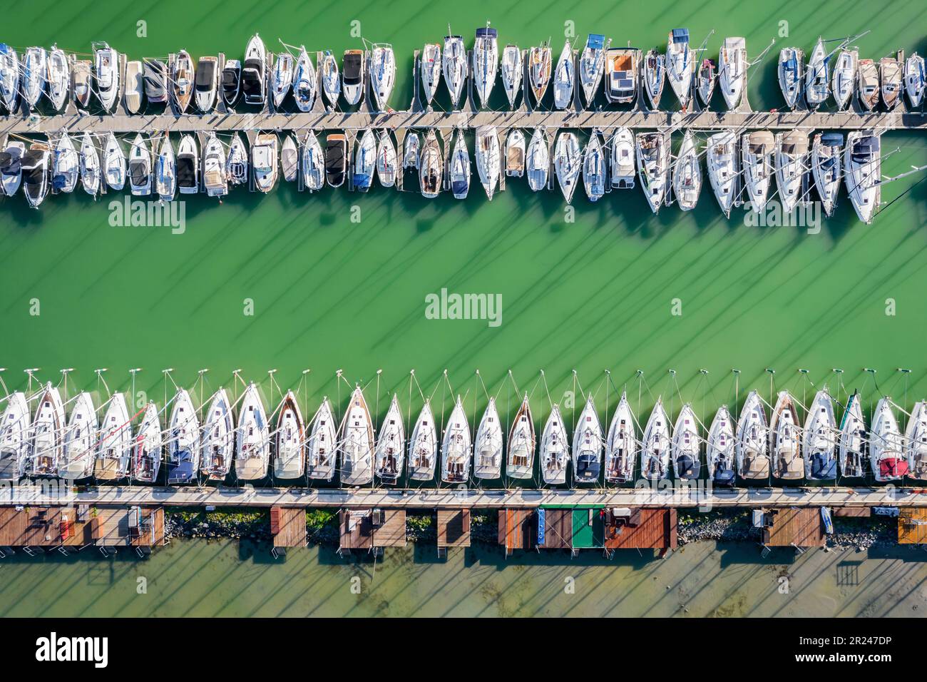 Vista dall'alto verso il basso sul porto di una barca. Vista dall'alto di uno Yacht club. Vista drone. Attracco barche a vela. Lago verde. Foto Stock