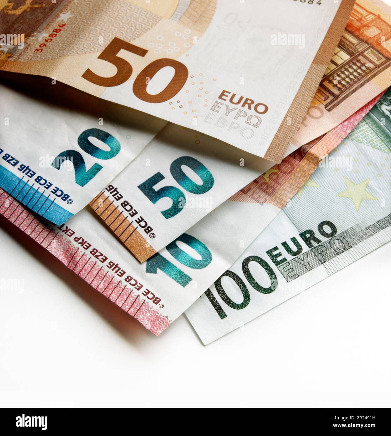 Vista ravvicinata. Messa a fuoco superficiale contro un mucchio di banconote in euro usate valori diversi con un effetto luce spot Foto Stock