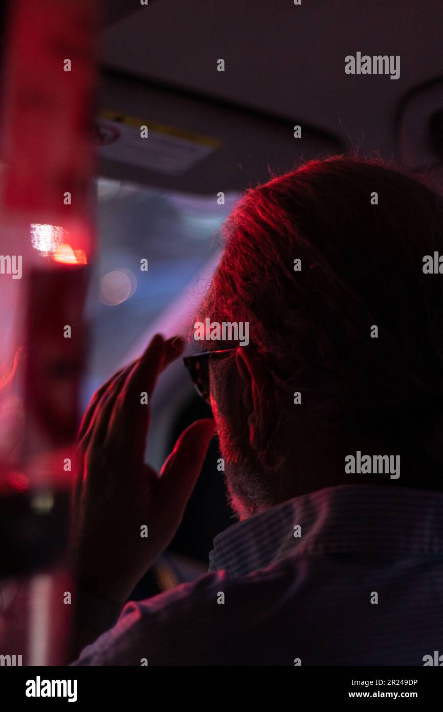 ritratto di un uomo anziano rivolto verso l'esterno con luce blu e rossa Foto Stock