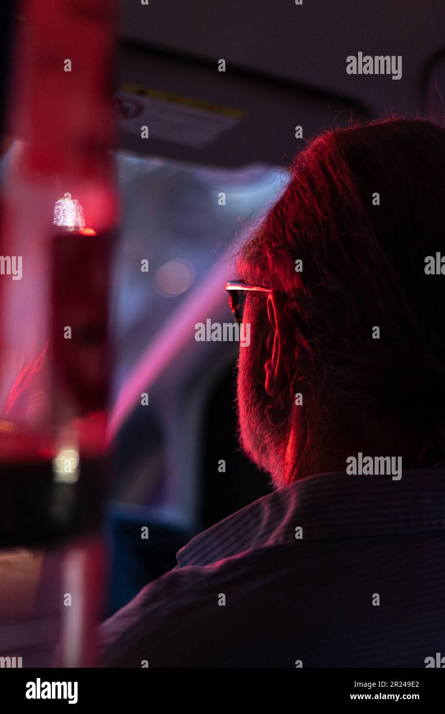 ritratto di un uomo anziano rivolto verso l'esterno con luce blu e rossa Foto Stock