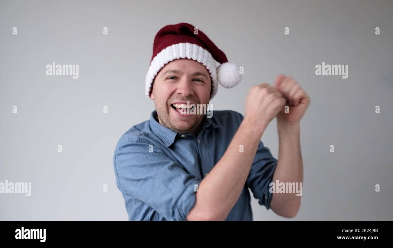 Il felice giovane europeo in un cappello di Capodanno balla con gioia alla festa. Foto da studio Foto Stock