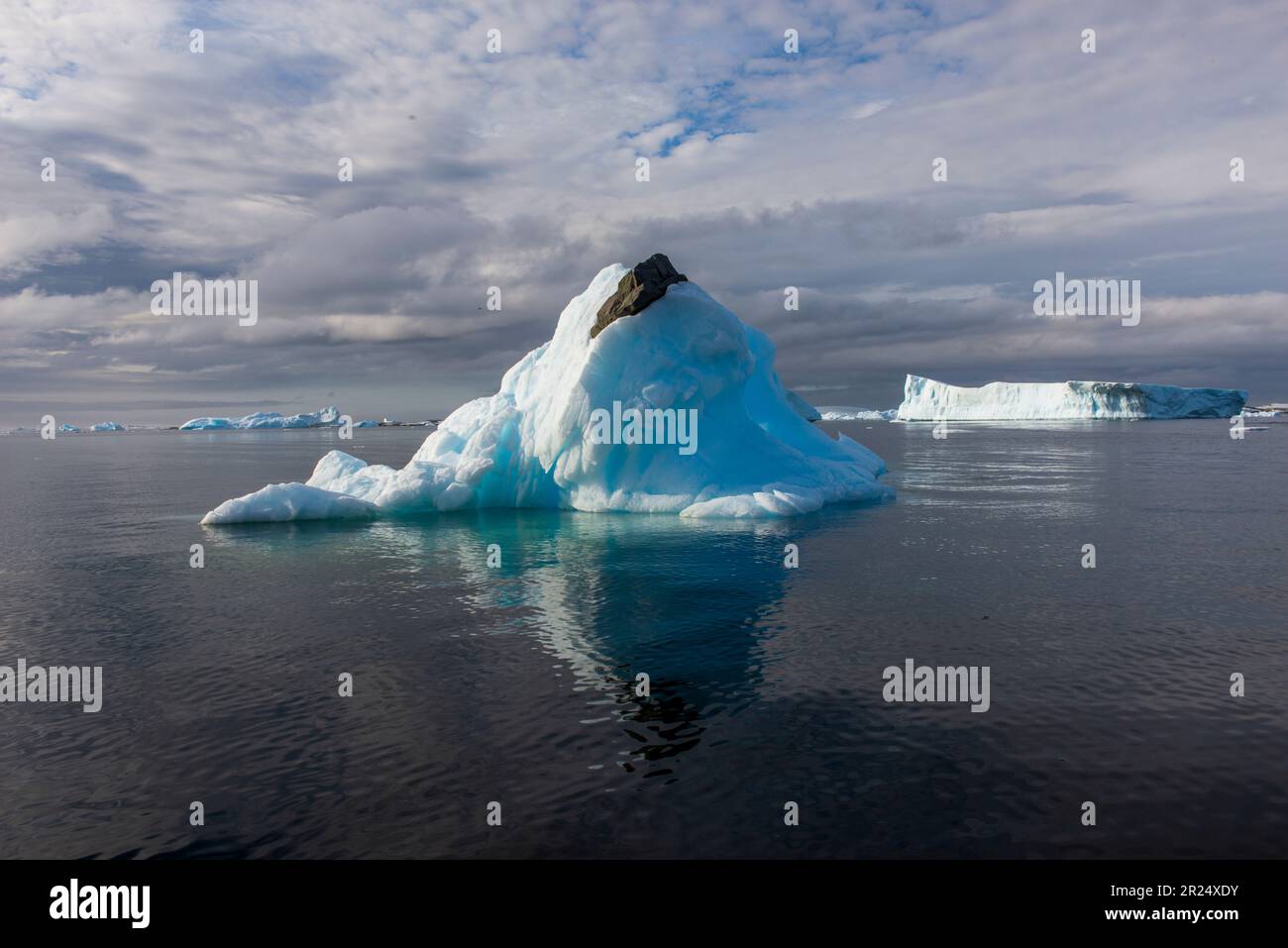 Passaggio francese, Antartide. Una roccia scorre attraverso la cima di un iceberg, una testimonianza del cambiamento climatico e dell'aria più calda. Foto Stock