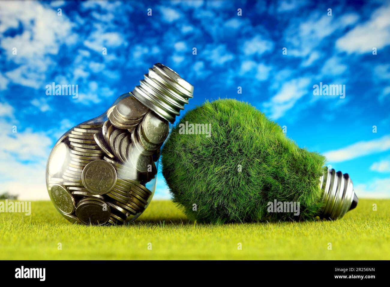 Monete all'interno della lampadina e lampadina verde eco con erba. Concetto di energia rinnovabile. I prezzi dell'elettricità, il risparmio energetico in famiglia. Foto Stock