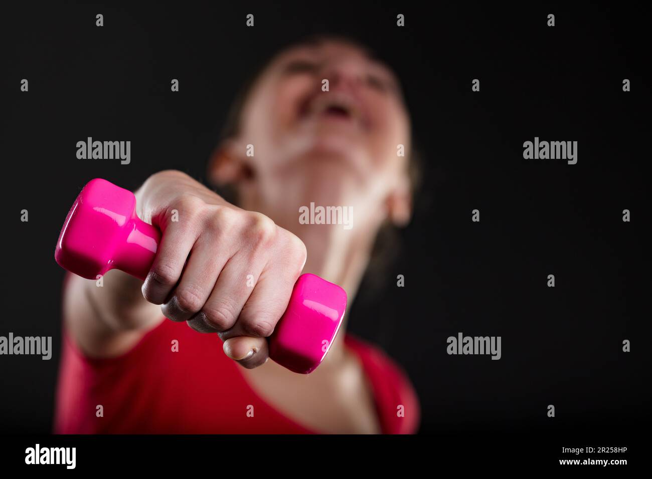 Donna fitness sollevamento peso rosa, sfocato sullo sfondo. Orgoglioso biondo, top rosso, che mostra gli obiettivi raggiunti. A stomaco piatto, uomo sana in corpi sano - i Foto Stock