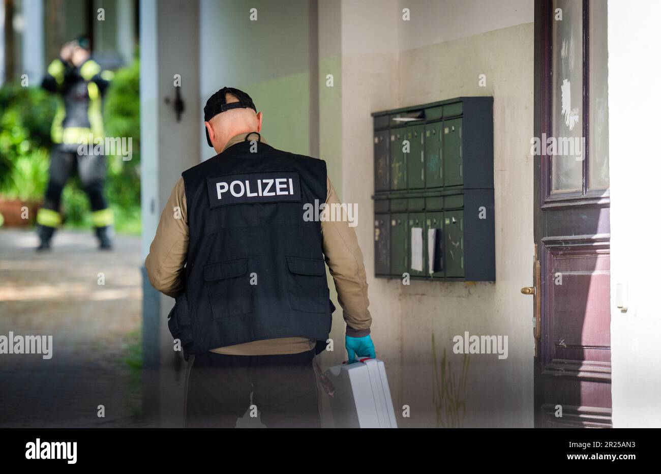 17 maggio 2023, Sassonia, Chemnitz: Un agente forense della polizia attraversa l'ingresso di un edificio di appartamenti a Kanalstraße, nel quartiere Schlossschemnitz. Durante un'operazione di polizia a Chemnitz, un uomo è stato ferito da colpi di polizia. Secondo la polizia, il 31 aveva in precedenza puntato sugli ufficiali con una balestra mercoledì. Una pallottola aveva colpito uno scudo di polizia. Dopo di che, il 31-year-old ha continuato a puntare l'arma contro gli ufficiali di polizia. Gli ufficiali poi raggiunsero per le loro armi di servizio e spararono diversi colpi. Il 31-year-old è stato colpito. È stato portato in ospedale. La polizia offi Foto Stock