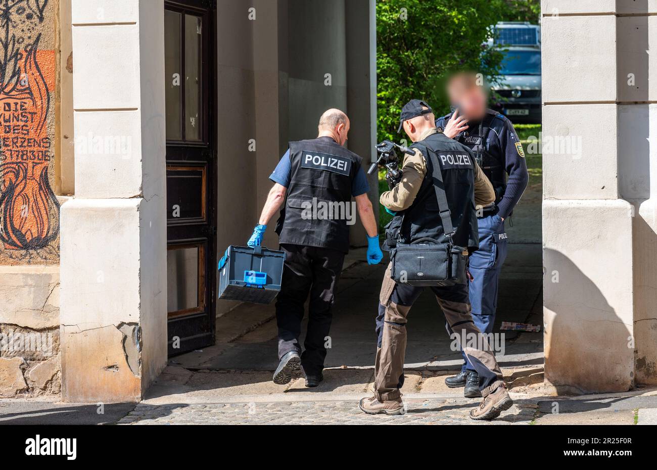 17 maggio 2023, Sassonia, Chemnitz: Gli ufficiali di polizia forense camminano attraverso l'ingresso di un edificio di appartamenti a Kanalstraße, nel quartiere Schlossschemnitz. Durante un'operazione di polizia a Chemnitz, un uomo è stato ferito da colpi di polizia. Secondo la polizia, il 31 aveva in precedenza puntato sugli ufficiali con una balestra mercoledì. Una pallottola aveva colpito uno scudo di polizia. Dopo di che, il 31-year-old ha continuato a puntare l'arma contro gli ufficiali di polizia. Gli ufficiali poi raggiunsero per le loro armi di servizio e spararono diversi colpi. Il 31-year-old è stato colpito. È stato portato in ospedale. L'ufficio di polizia Foto Stock