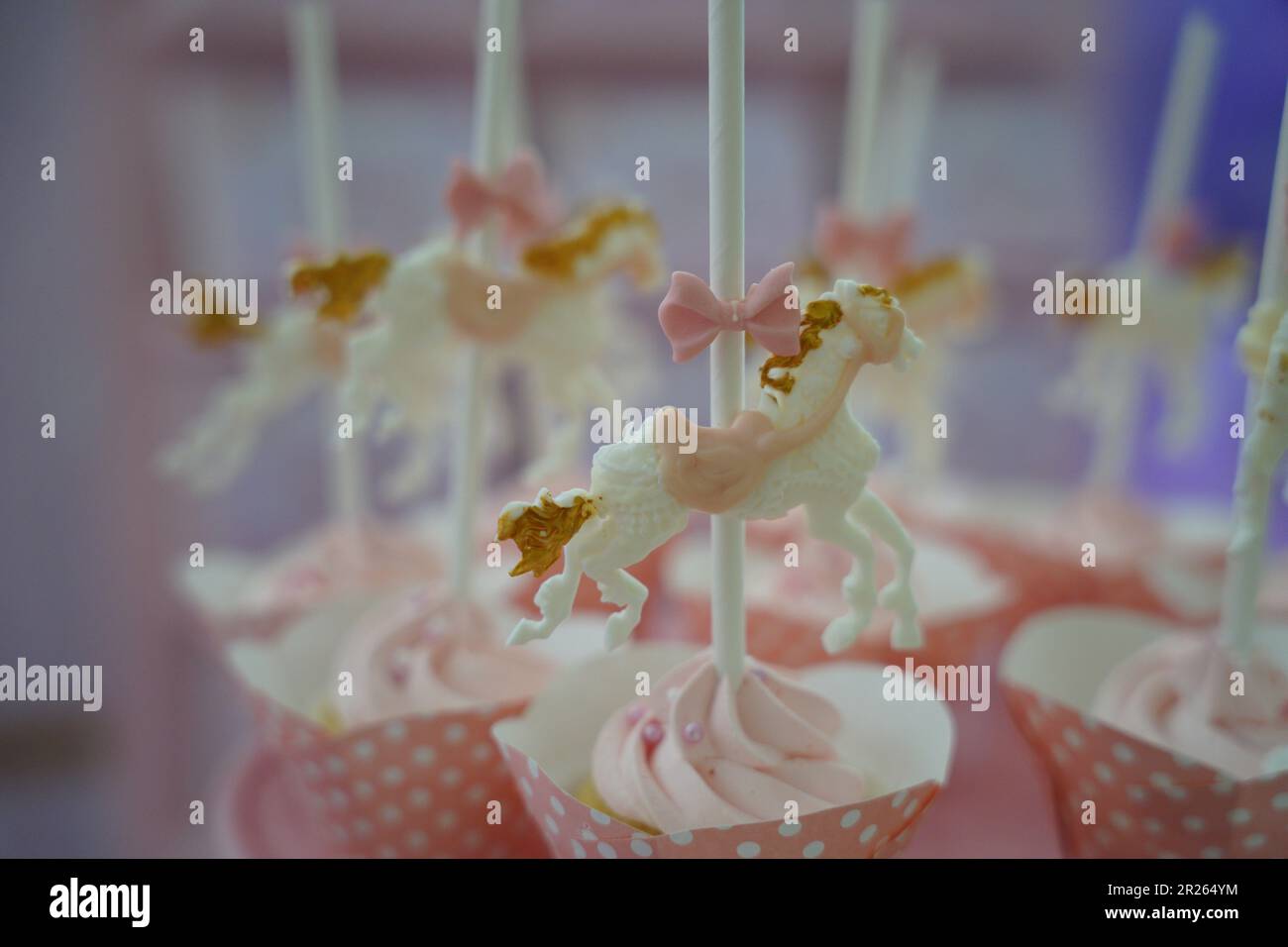 Cupcakes carino fantasia. Carosello cavallo oro e cupcakes rosa. Caramelle per feste a tema carosello per catering. Foto Stock